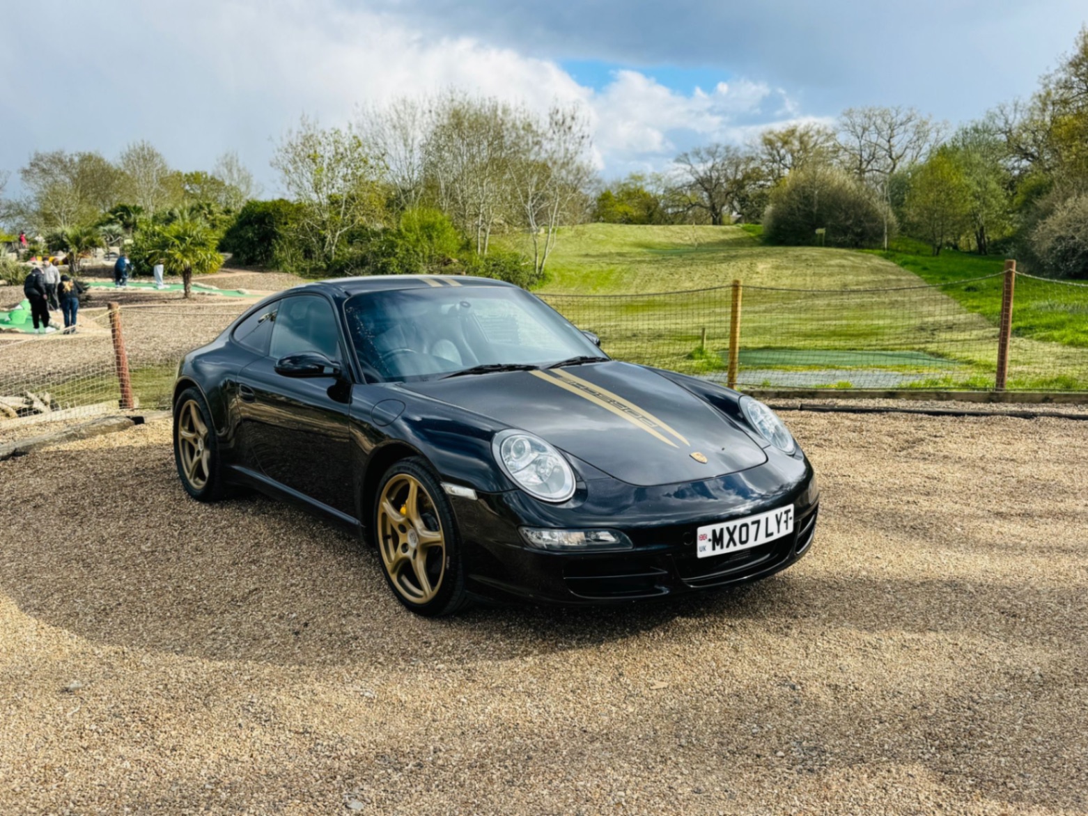 Porsche 911 Carrera 997 front three-quarter in black with gold stripes
